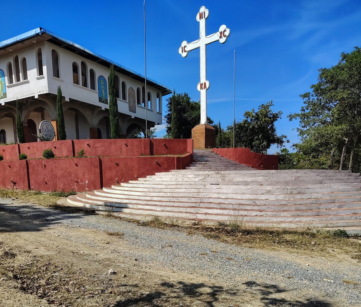 A church building in the highlands with a tall white cross at the top of its steps
