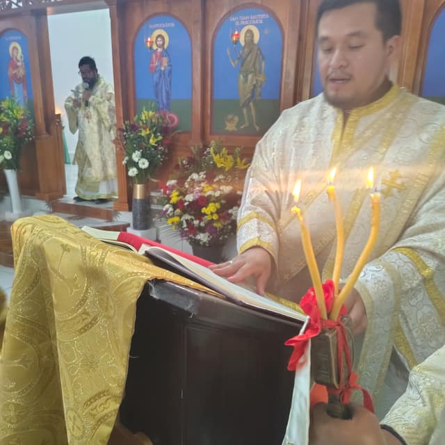 A priest lighting candles at the Gospel stand during the liturgy