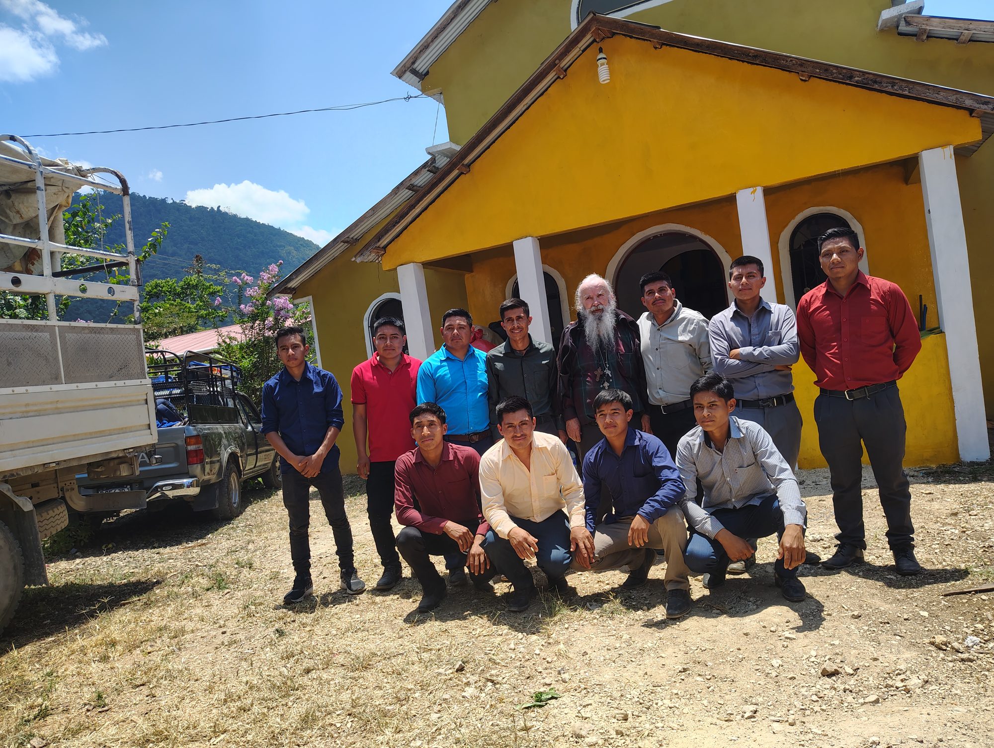 Young men of the parish with a visitor outside a yellow church in the highlands
